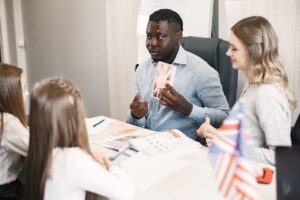 Teacher guiding diverse students in an English language lesson with a British flag card. - Photo by Gustavo Fring on Pexels