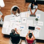 A diverse group working on marketing strategies with charts and laptops in an office setting. - Photo by Kindel Media on Pexels