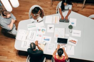 A diverse group working on marketing strategies with charts and laptops in an office setting. - Photo by Kindel Media on Pexels