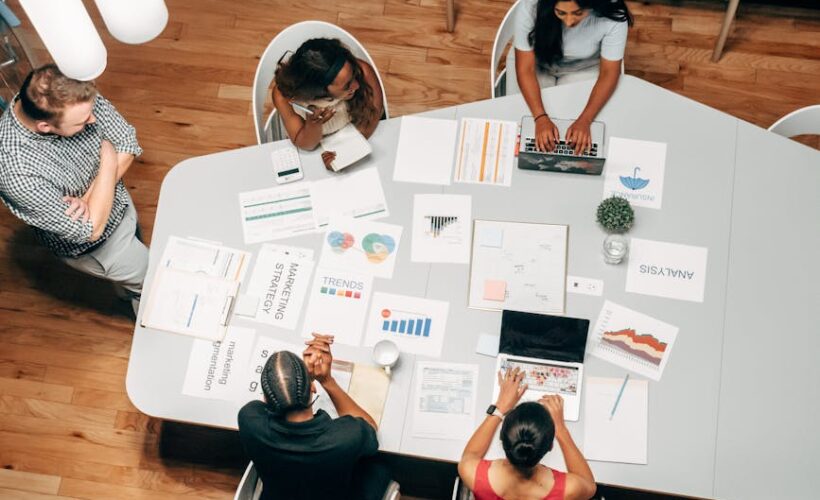 A diverse group working on marketing strategies with charts and laptops in an office setting. - Photo by Kindel Media on Pexels