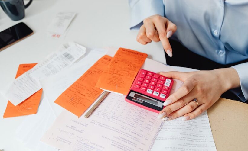 Businesswoman calculates expenses using receipts and calculator at desk. Ideal for finance, accounting themes. - Photo by www.kaboompics.com on Pexels