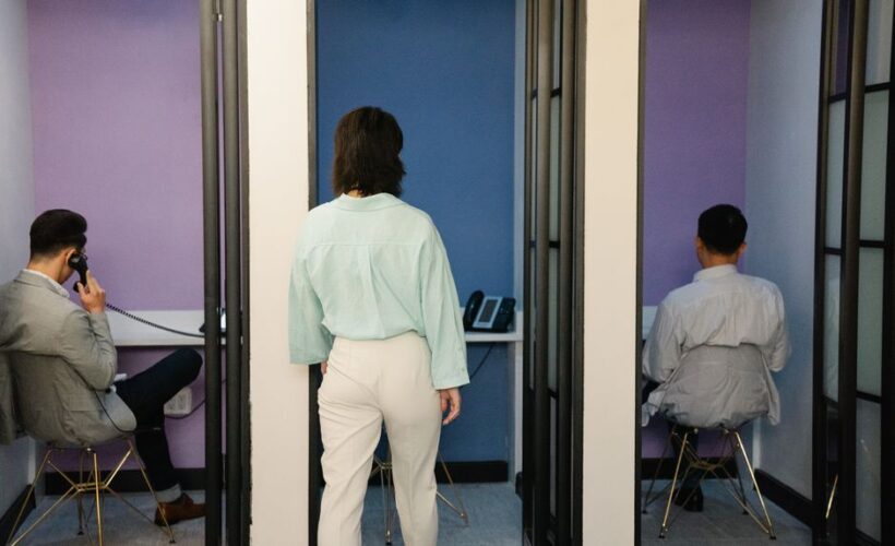 Three people in a modern office using phone booths for focused work. - Photo by Felicity Tai on Pexels
