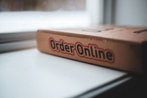 Soft focus of cardboard box of delivery pizza online service placed on white windowsill in daylight - Photo by Erik Mclean on Pexels