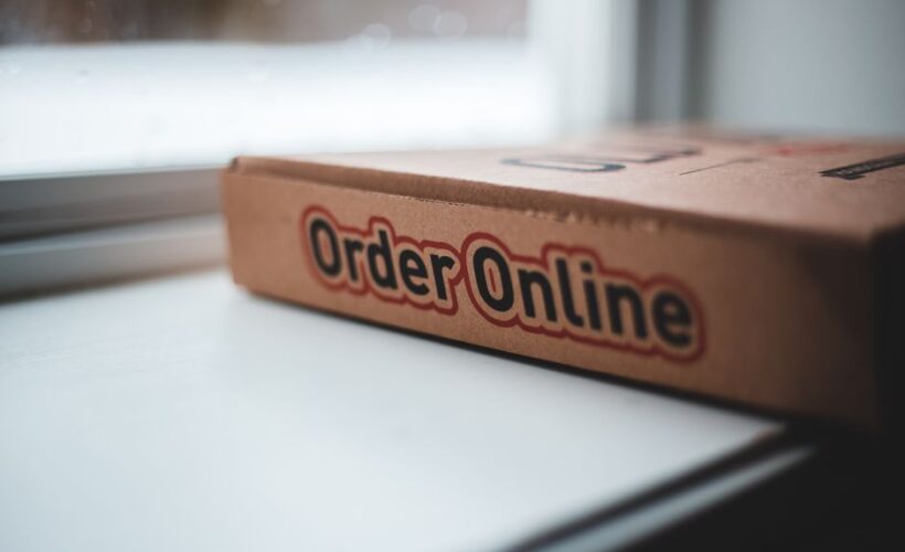 Soft focus of cardboard box of delivery pizza online service placed on white windowsill in daylight - Photo by Erik Mclean on Pexels